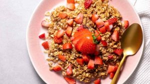 A plate full of baked oatmeal topped with strawberries.