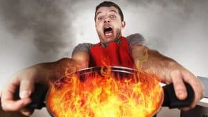 A man holding a burning pot with a look of panic on his face.