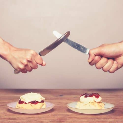 Two people fighting with knives over scones.
