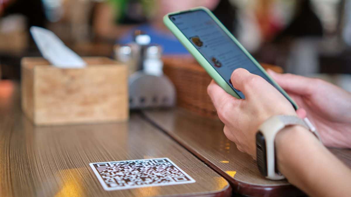 A person using their phone to access a menu via a QR code.