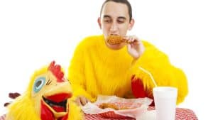 A person in a chicken uniform eating chicken wings.