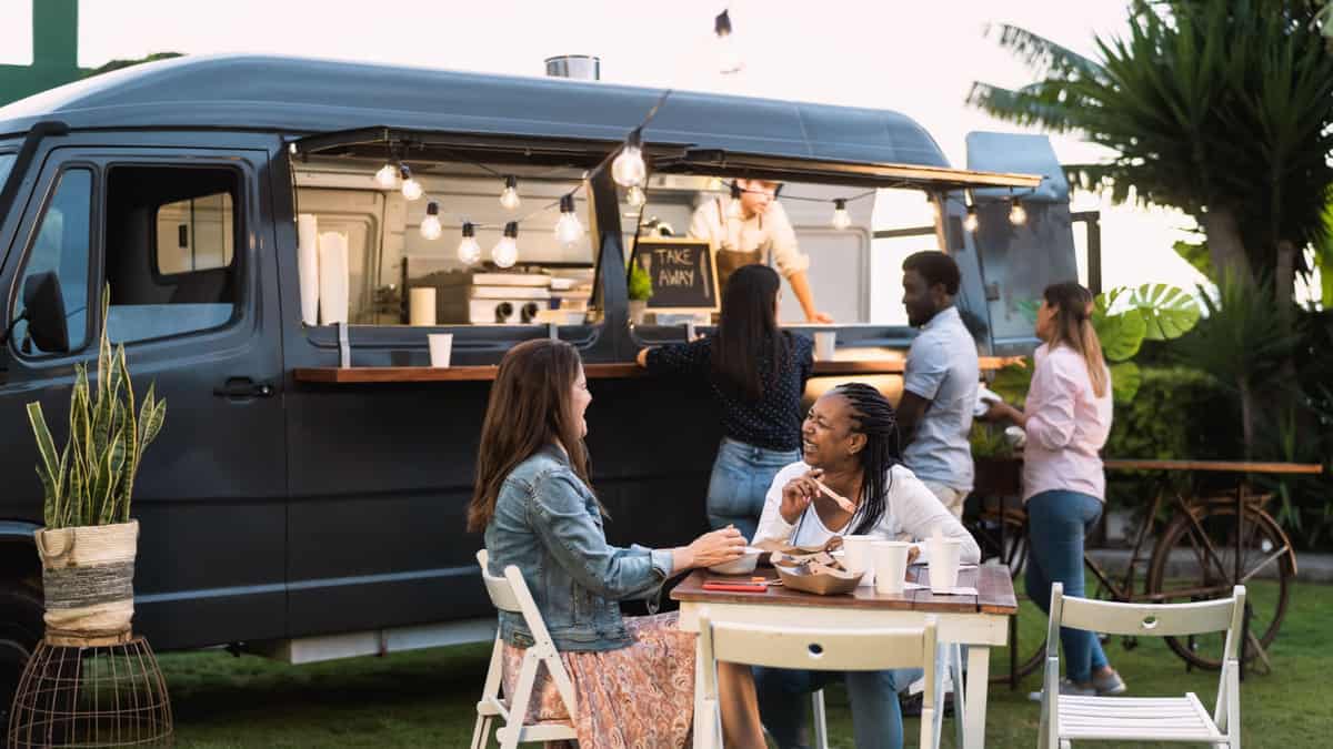 People eating in front of a food truck.