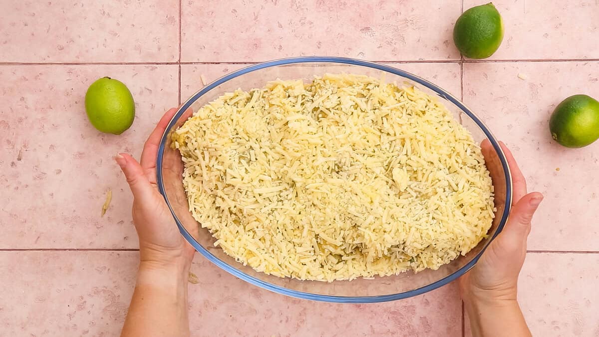 Chicken enchiladas topped with sauce and cheese, before baking.