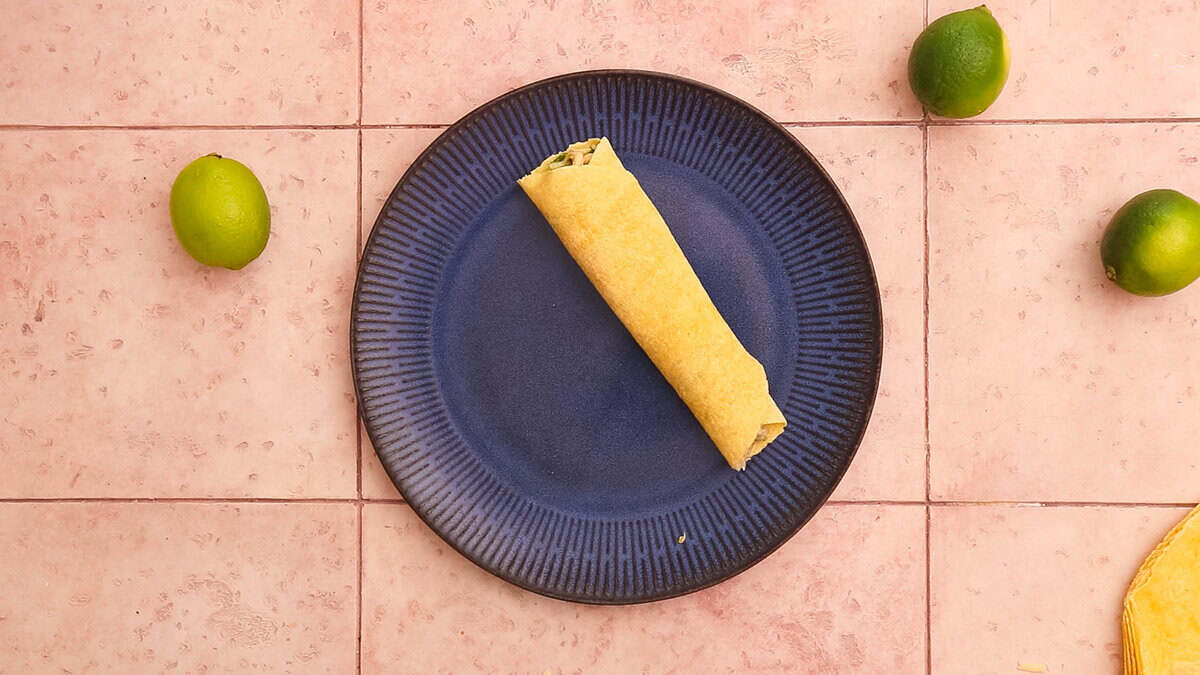 A chicken enchilada after wrapping it and before placing it in the baking dish.