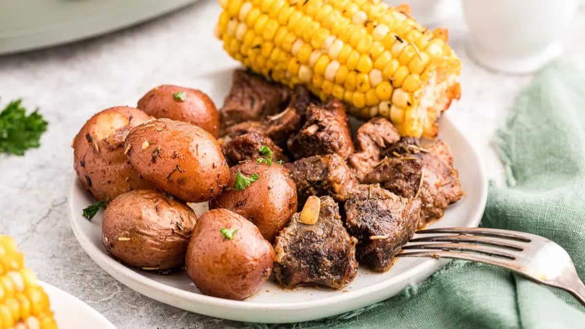 A plate with steak, potatoes and corn.
