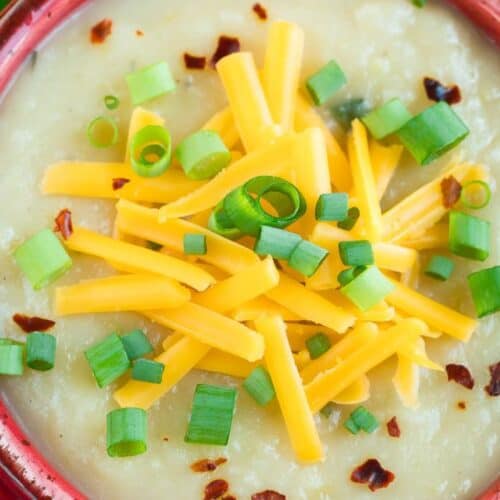 A bowl of loaded baked potato soup topped with cheese.