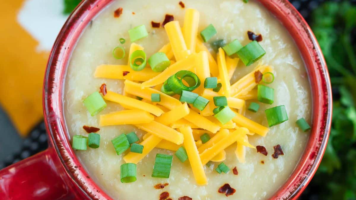 A bowl of loaded baked potato soup topped with cheese.