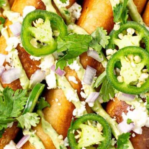 Flautas topped with jalapenos and sauce.