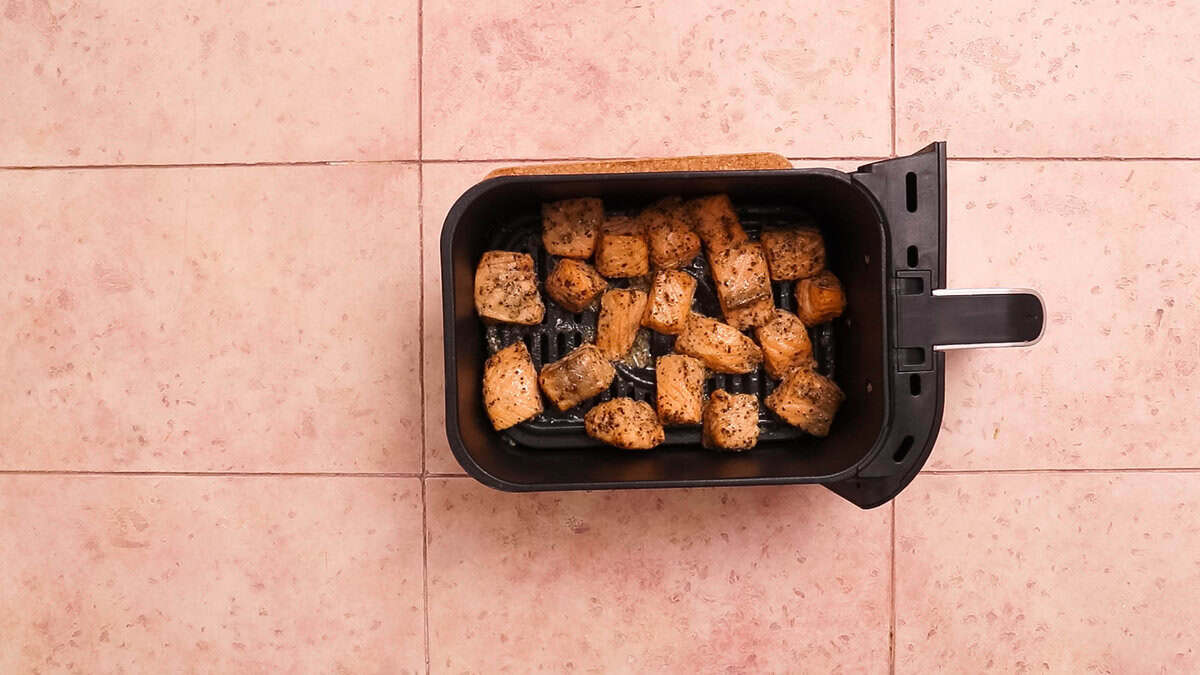 Air fryer salmon bites in an air fryer basket after cooking.