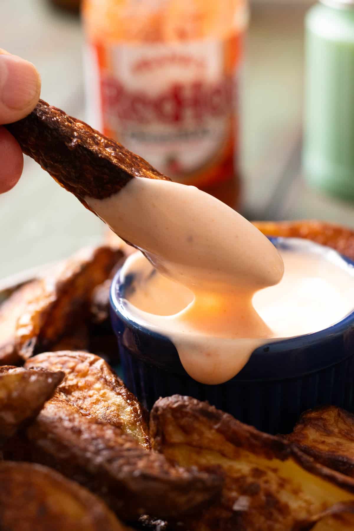 A steak fry being dipped in buffalo dipping sauce.