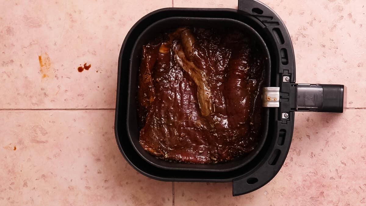 Skirt steak or flank steak in an air fryer before cooking.