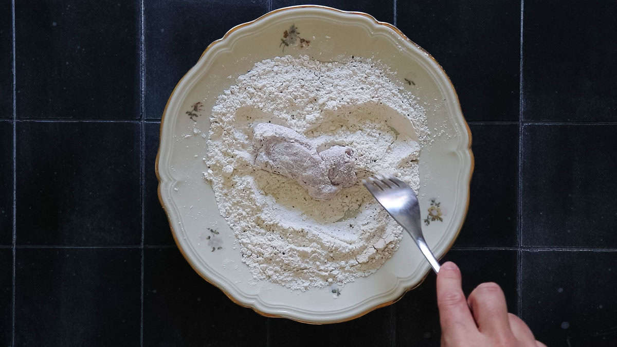 Coating chicken in flour.