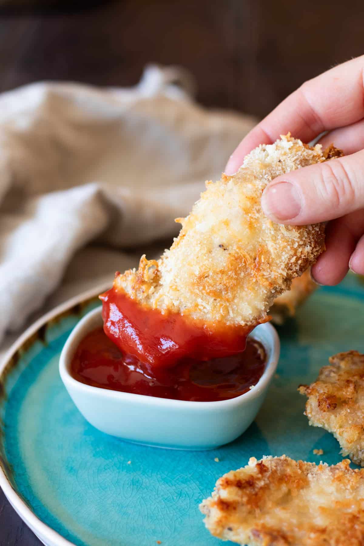 Dipping chicken in ketchup.