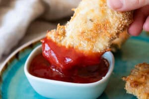 Dipping chicken in ketchup.