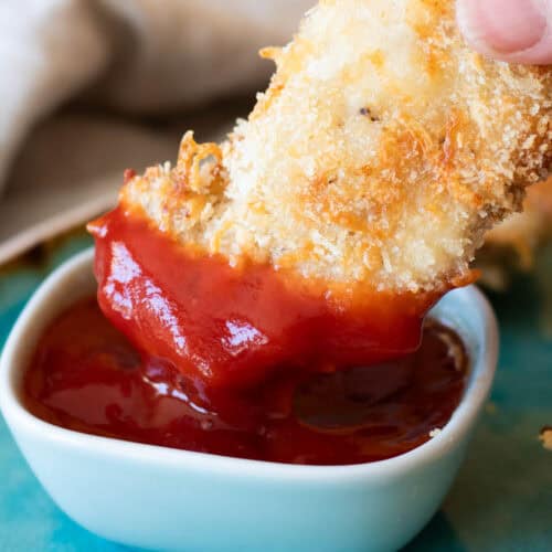 Dipping chicken in ketchup.