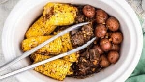 Steak potatoes and corn in slow cooker.