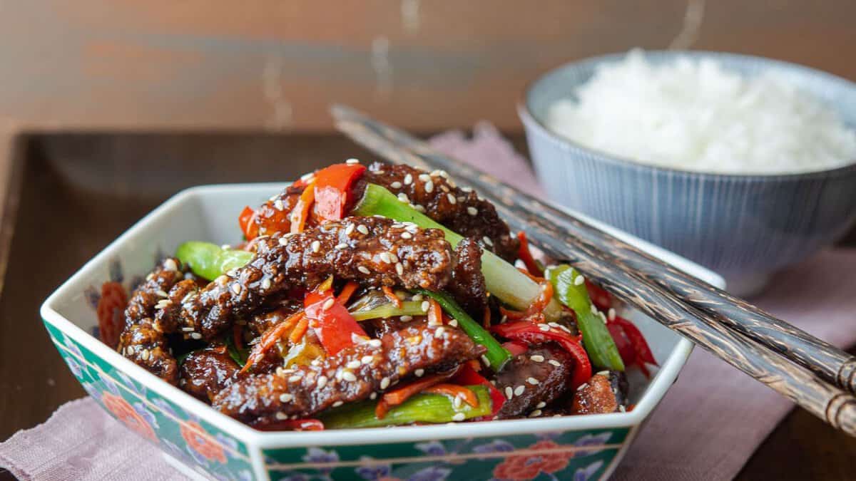 A bowl of Chinese crispy beef with chopsticks.