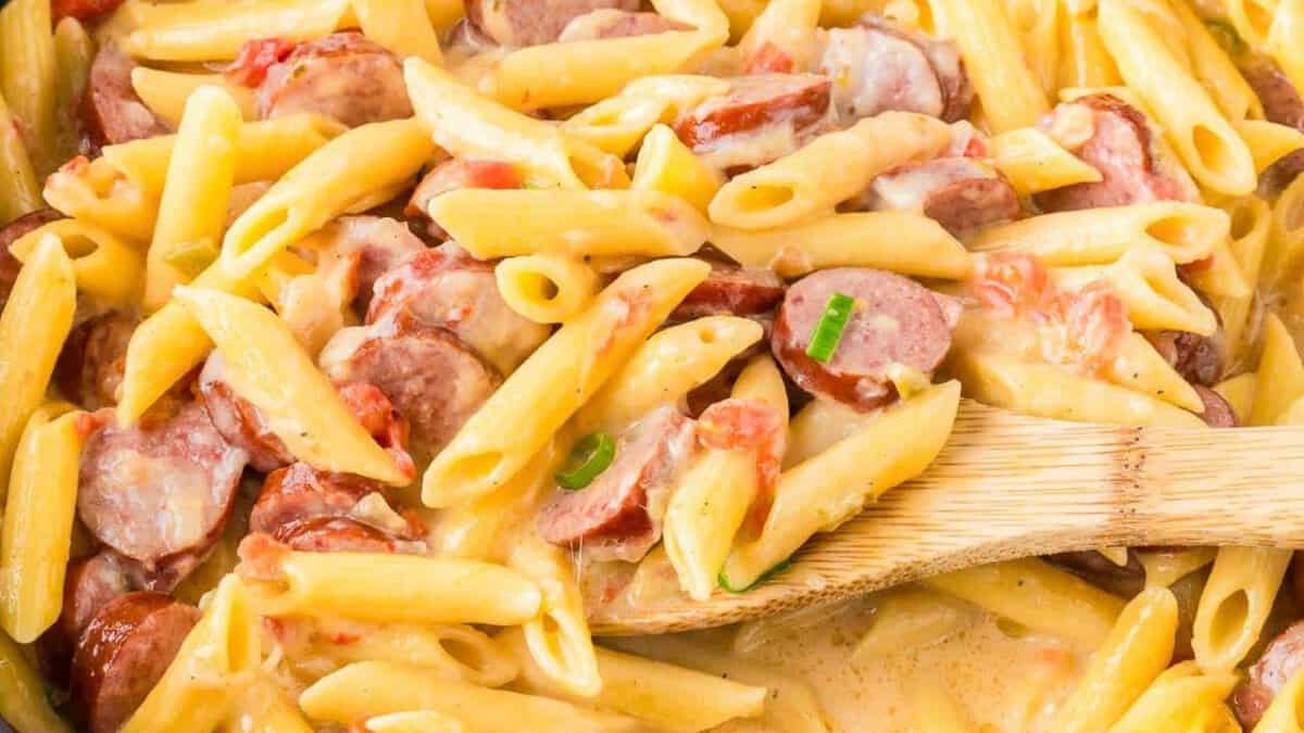 Cheesy smoked sausage pasta on a skillet.