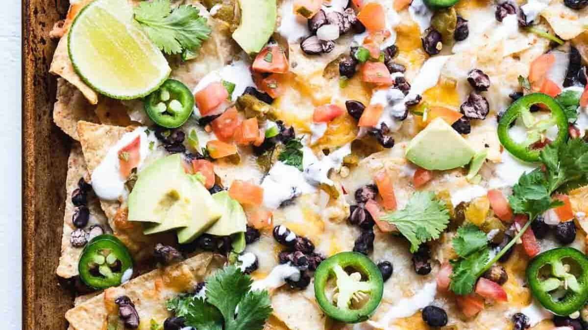 Oven baked nachos with cheese and lime wedges.