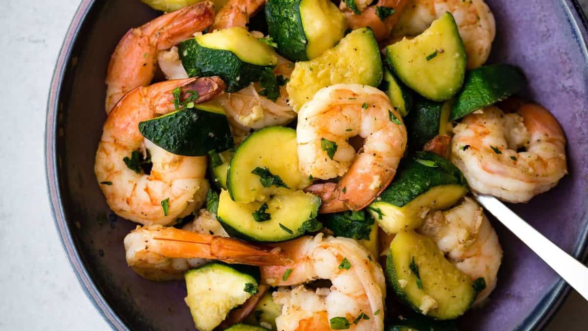 A bowl of shrimp with zucchini.