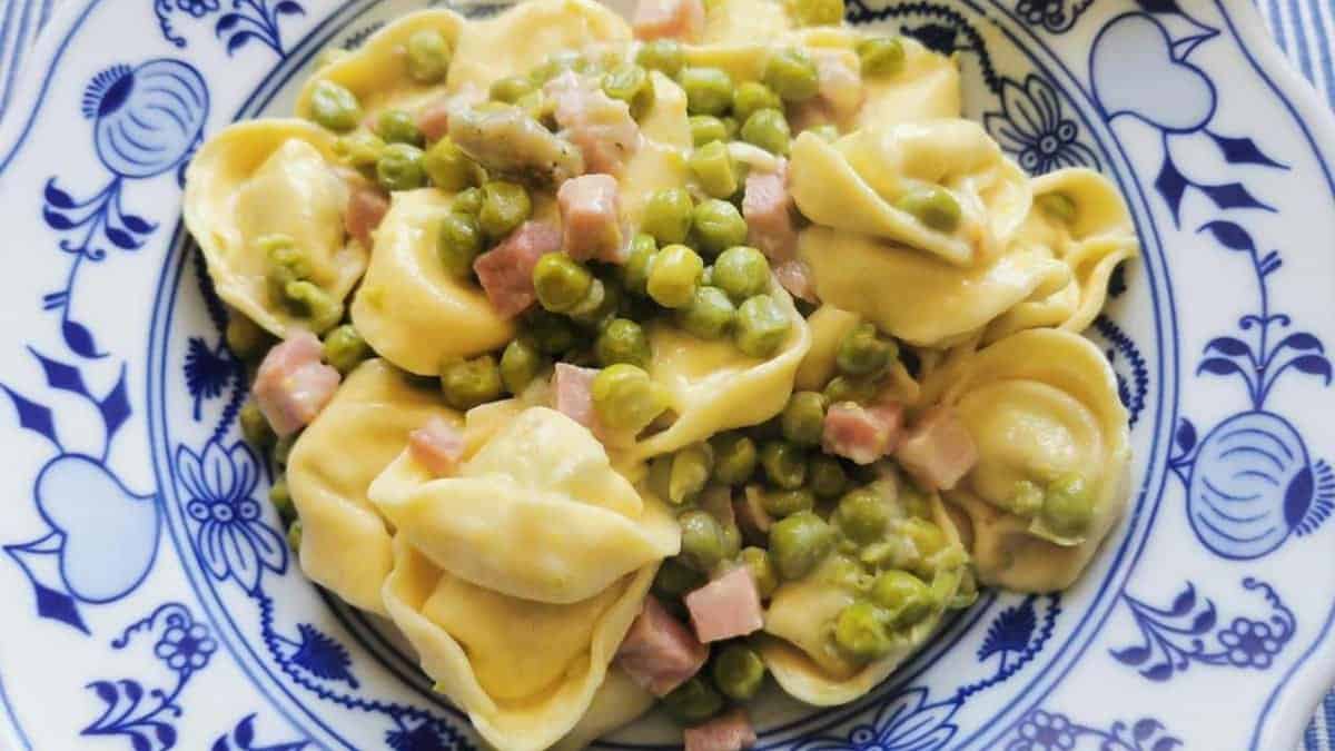 Tortellini with ham and peas on a plate.