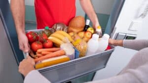 Man handing over groceries in a box.