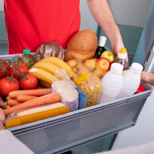 Man handing over groceries in a box.
