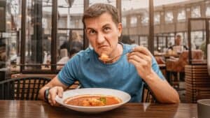 A man eating food who looks disgusted.