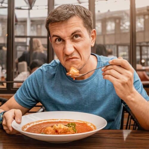 A man eating food who looks disgusted.