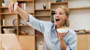 A woman taking a selfie while eating food.