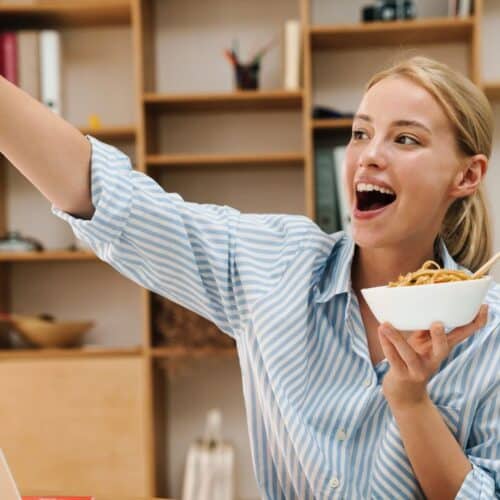 A woman taking a selfie while eating food.