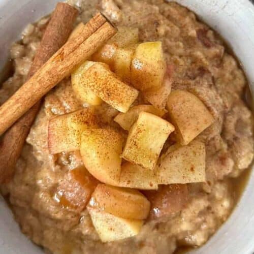 A bowl of oatmeal with apples.