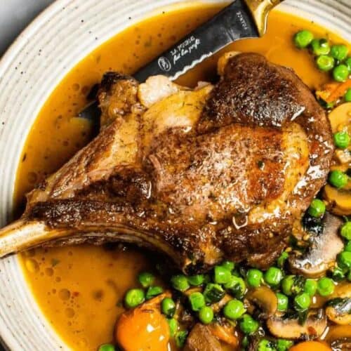 A pork chop with mushrooms and veggies.