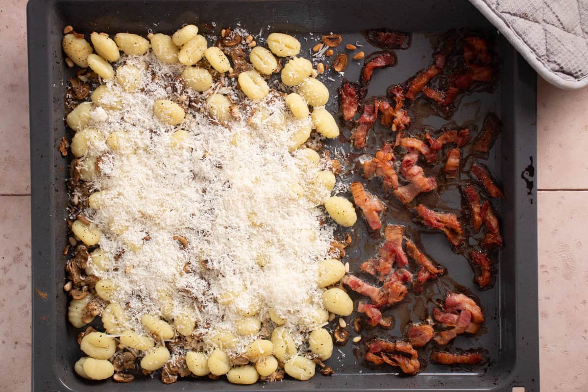 A sheet pan with gnocchi on one side and bacon on the other side, after cooking.