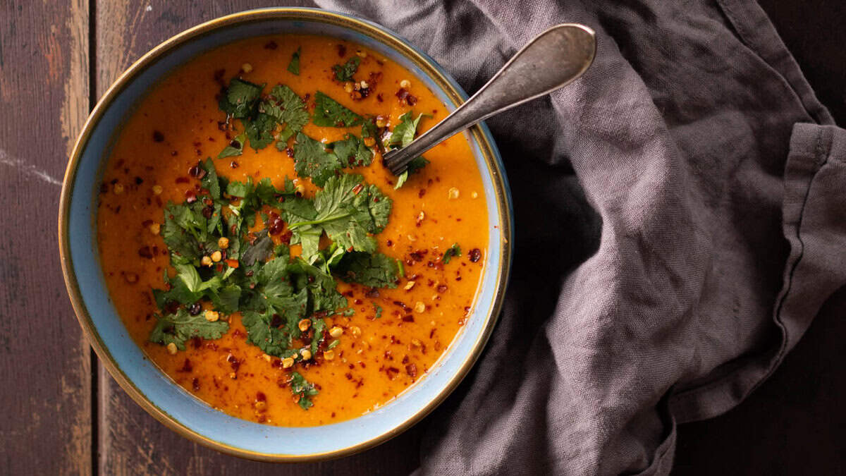 A bowl of coconut lentil soup topped with chili flakes and cilantro.
