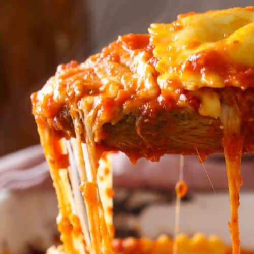 A spoonful of lazy lasagna being lifted out of a baking dish with an amazing cheese pull.