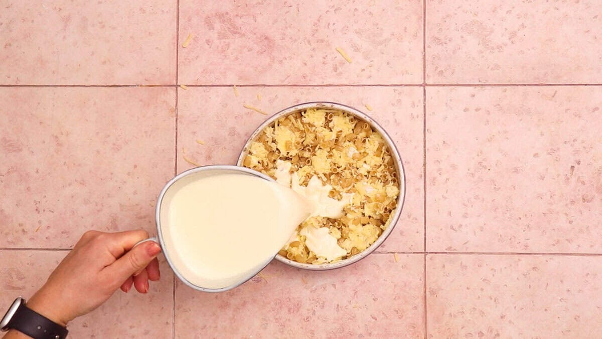 Pouring cream over mac and cheese.