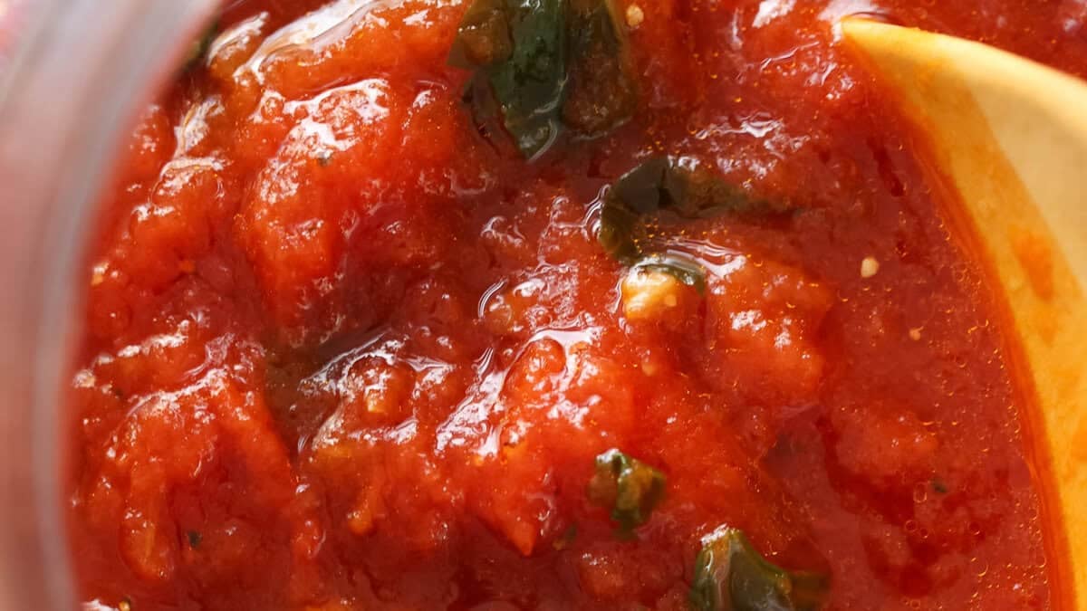 Close up of a jar of homemade tomato sauce with basil.