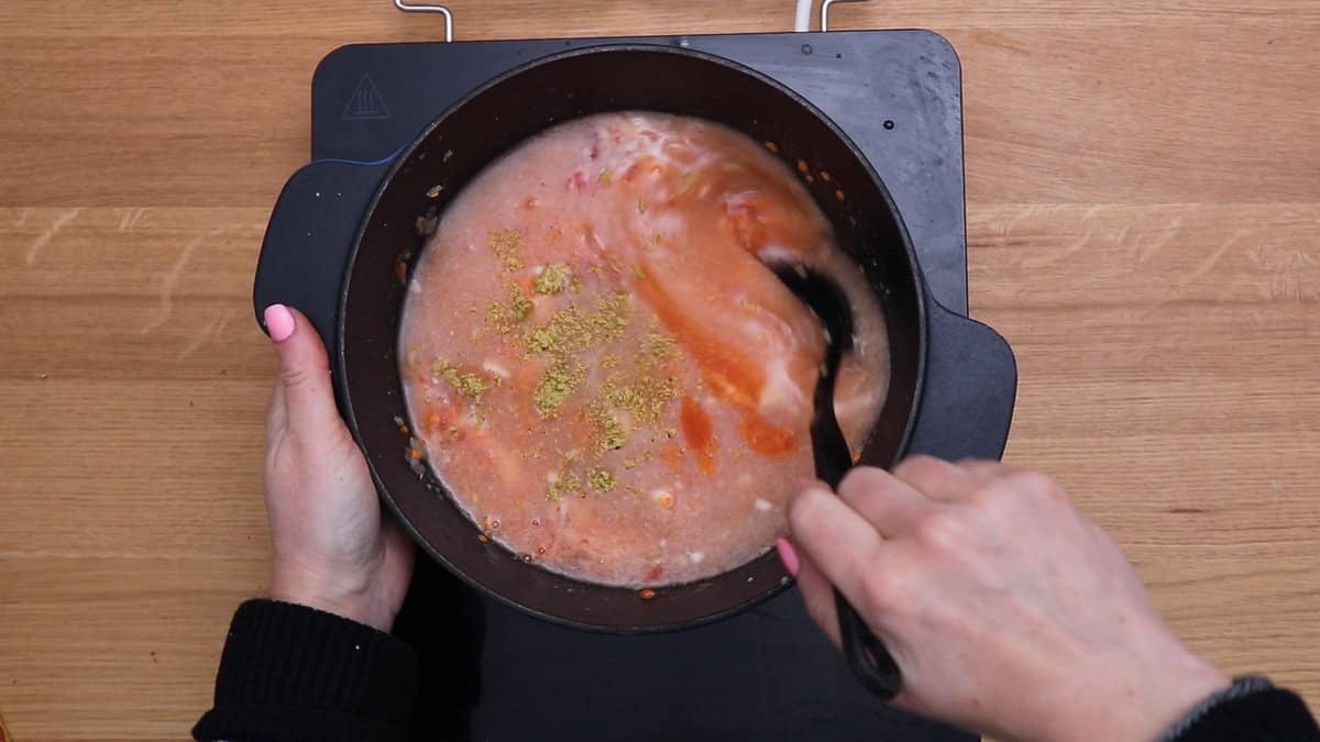 Mixing in water and coconut milk in lentil soup.