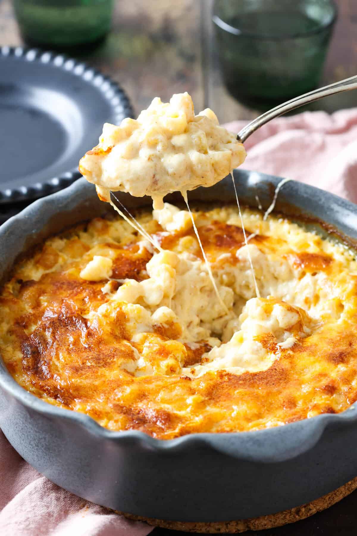 A spoonful of 3 cheese mac and cheese lifted out of a baking dish.