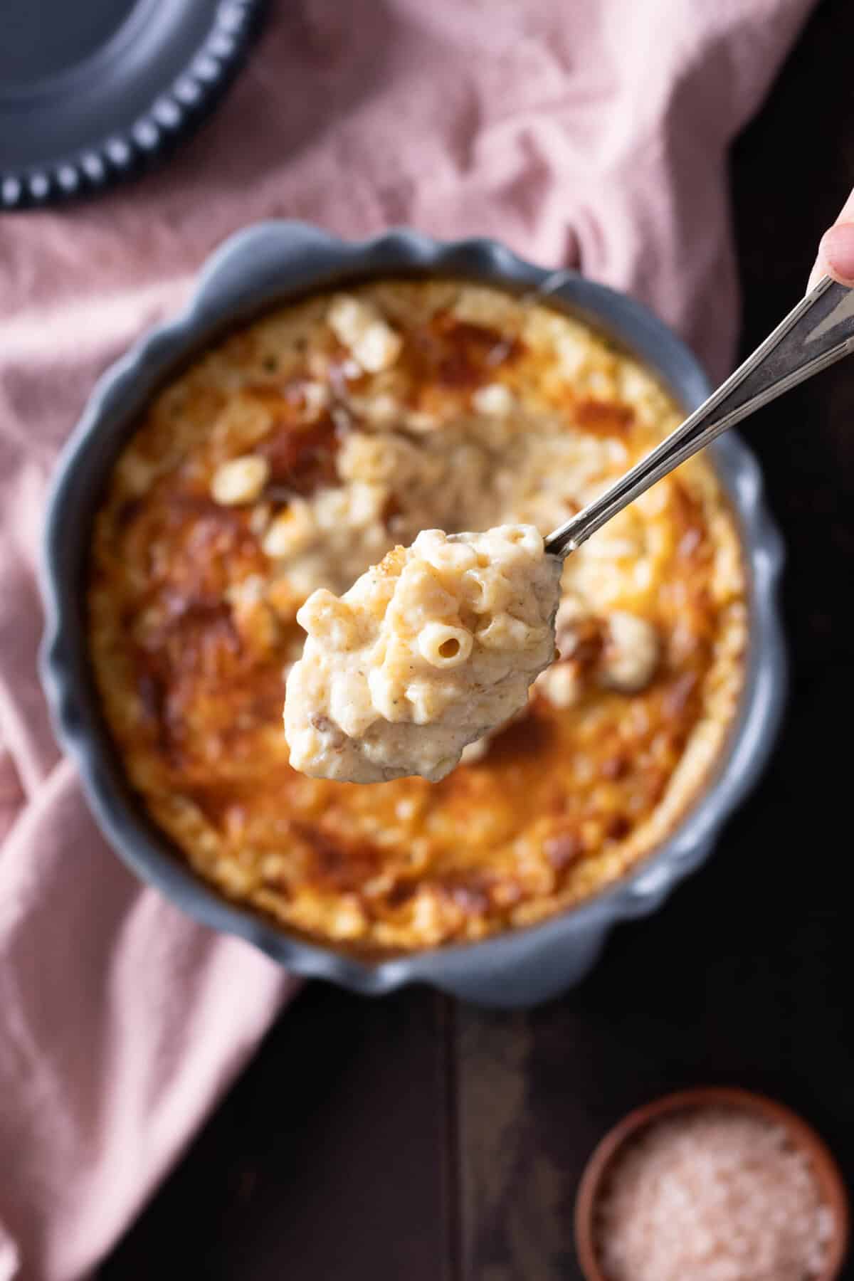 A spoonful of 3 cheese mac and cheese lifted out of a baking dish.