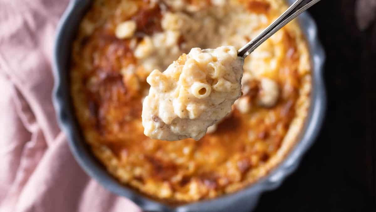 A spoonful of 3 cheese mac and cheese lifted out of a baking dish.
