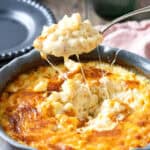 A spoonful of 3 cheese mac and cheese lifted out of a baking dish.