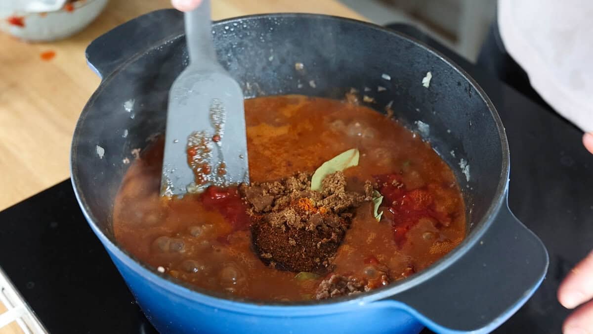 Adding spices to beef chili.
