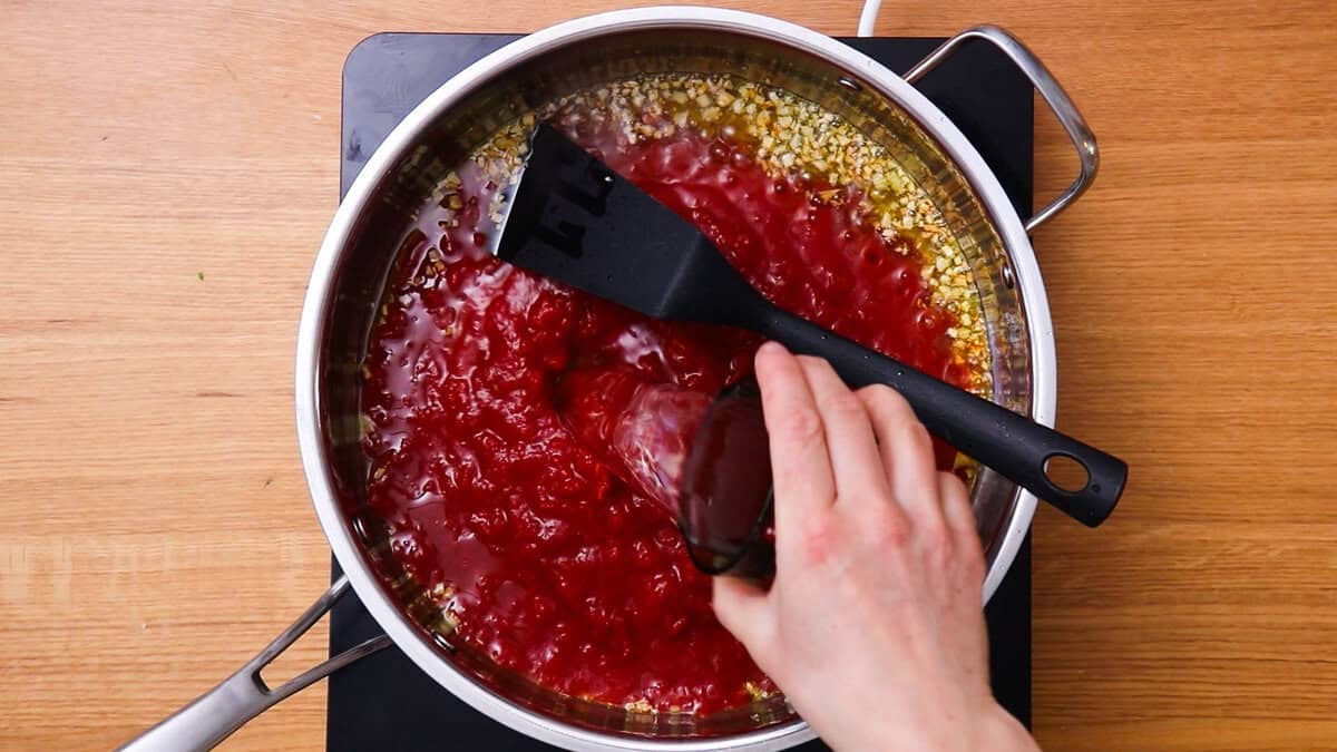 Adding white wine to make an easy tomato sauce.