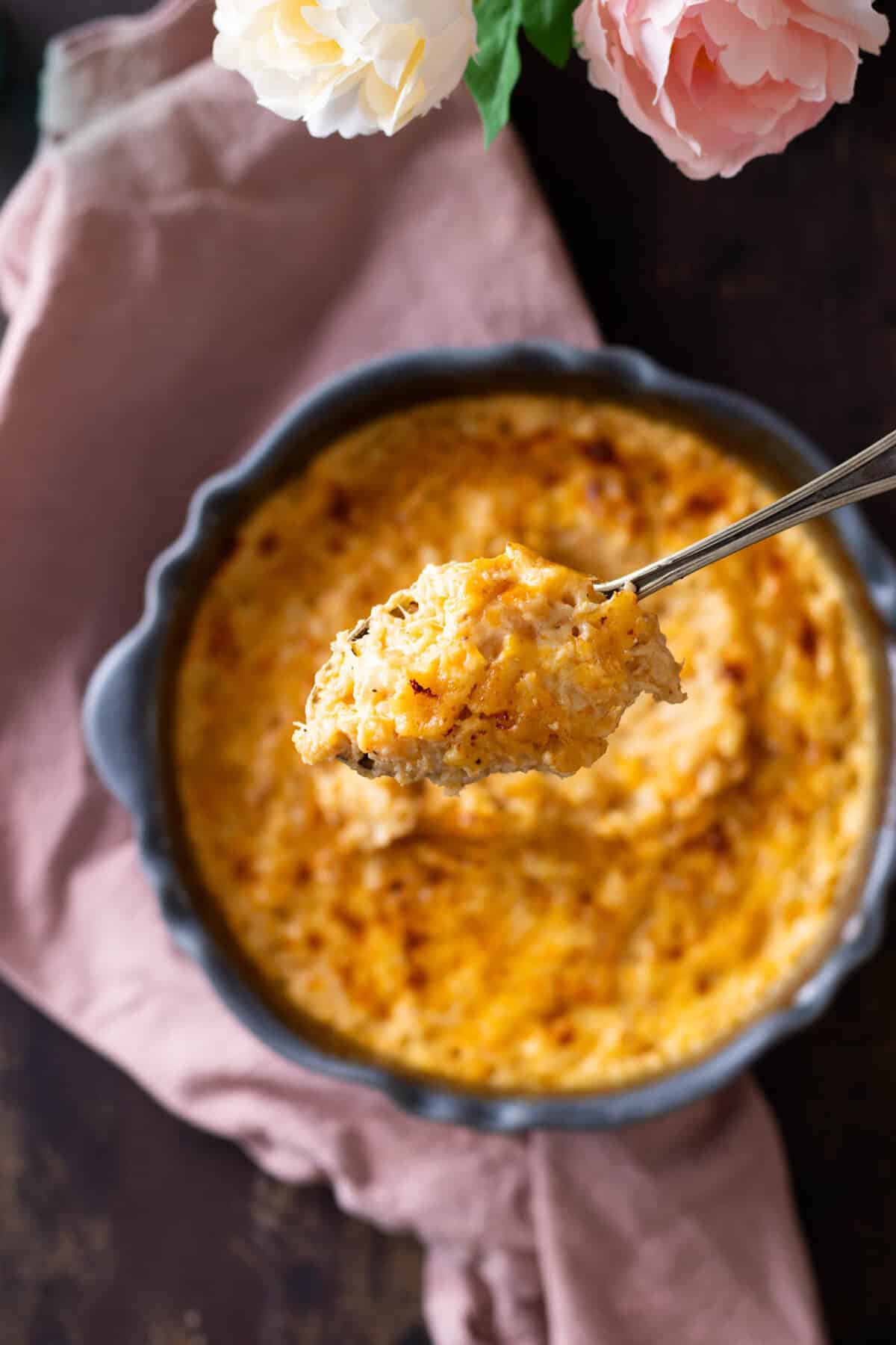 A spoonful of gouda mac and cheese being lifted out of the pan.