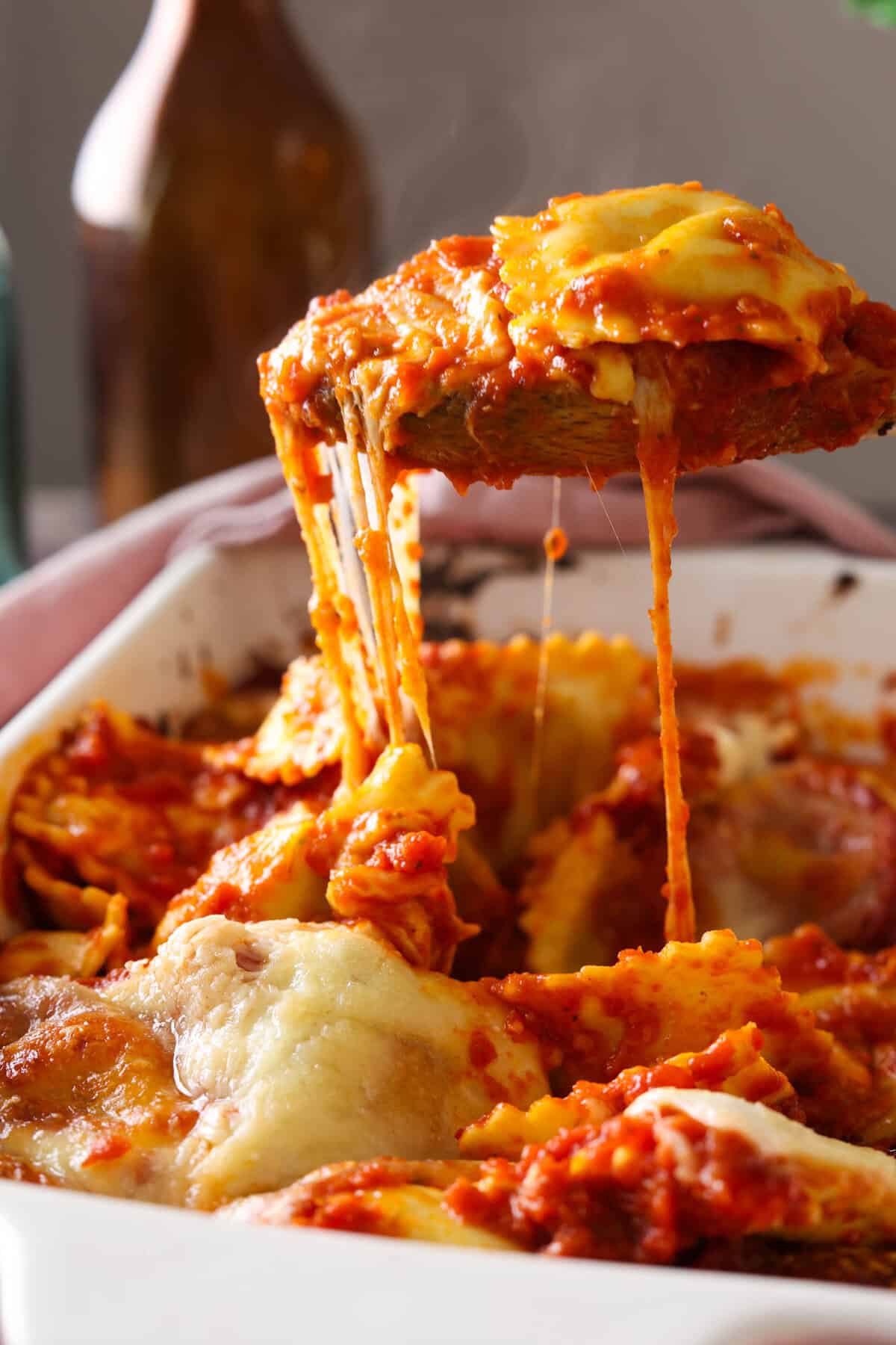 A spoonful of lazy lasagna being lifted out of a baking dish with an amazing cheese pull.