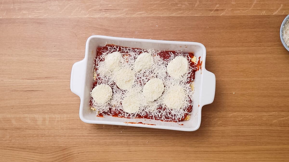 The first layer of a lazy lasagna, ravioli and tomato sauce topped with mozzarella cheese and parmesan.