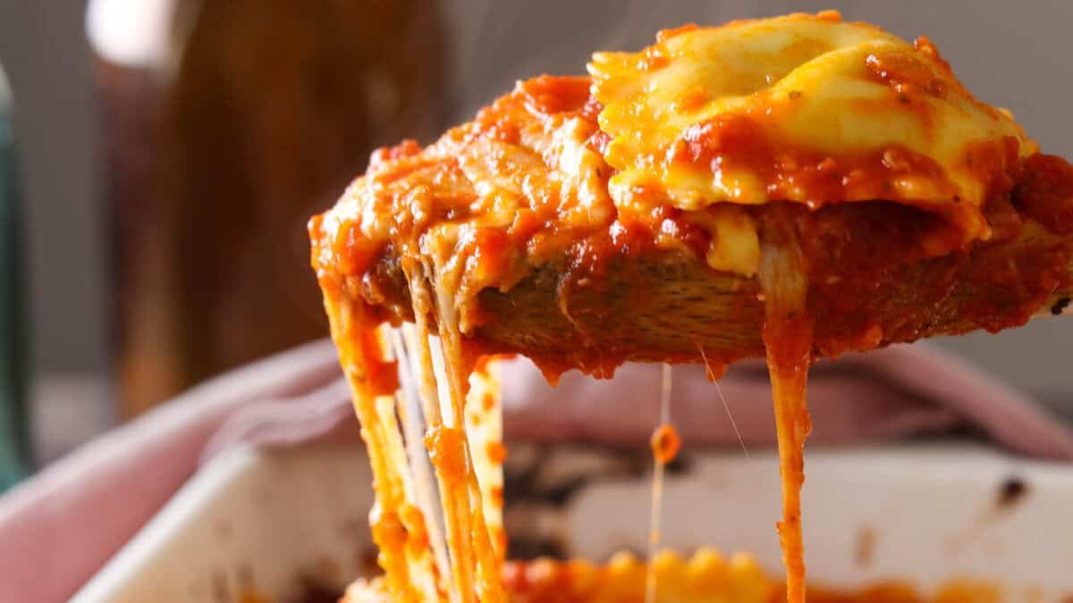 A spoonful of lazy lasagna being lifted out of a baking dish with an amazing cheese pull.