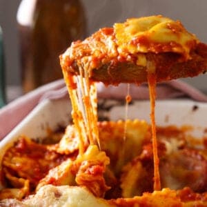 A spoonful of lazy lasagna being lifted out of a baking dish with an amazing cheese pull.